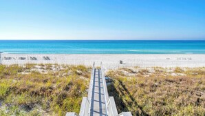 A beach with a wooden walkway leading to the shore, sandy beach, and ocean.