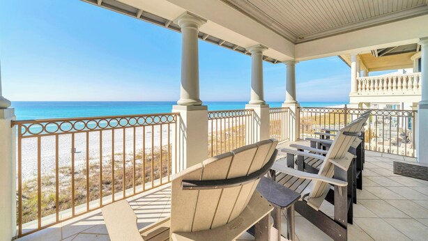 A covered outdoor area with chairs and a view of the beach.