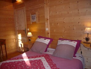 Habitació d'una cabana de fusta amb dos llits, cada un amb una làmpada en forma de cor.