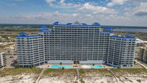 A large hotel with multiple floors, a central swimming pool, and a beach area. - Lighthouse 608 - Great Location on the Gulf-Gulf Shores-Signature Properties (Gulf Shores)