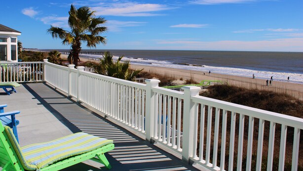 A balcony with a view of the beach and ocean.