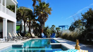 A swimming pool with lounge chairs, palm trees, and a pineapple decoration.