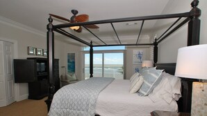 A four-poster bed with a view of the ocean, a television, and a lamp on a nightstand. - OCEANFRONT / Sleeps 14 / BISHOPS / POOL / ELEVATOR / SUMMER KITCHEN (Isle of Palms)