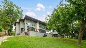 Et moderne hus i to etager med en overdækket terrasse og en velplejet græsplæne.