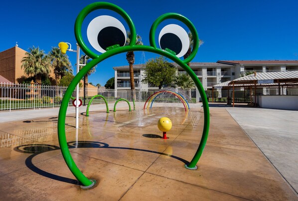A playground with a frog-shaped water play structure.