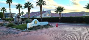 A sign for Las Palmas Resort Condominiums with a landscaped garden, palm trees, and a paved entrance.