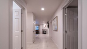 A hallway with white walls and doors, leading to a living area with a fireplace. - Spacious Family Condo  Ground Floor, Patio, Pools & Bikes & Fun All YEAR-ROUND  (St George)