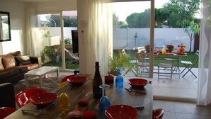 Ein modernes Wohnzimmer mit Essbereich, großen Schiebeglastüren, die zu einem Garten führen, und Blick ins Freie.