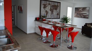 Eine moderne Küche mit Kochinsel, roten Barhocker und einer großen Weltkarte an der Wand.