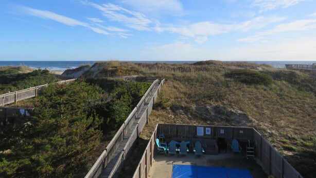 A beachside wooden structure with a blue tarp, wooden benches, and a wooden walkway. - Last minute special/Ocean Front/ Pool, Pool Table/pet friendly (Nags Head)