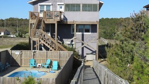 A two-story house with a wooden deck, a swimming pool, and a fenced backyard. - Last minute special/Ocean Front/ Pool, Pool Table/pet friendly (Nags Head)