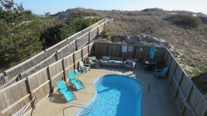 A backyard with a swimming pool, wooden deck, and outdoor furniture. - Last minute special/Ocean Front/ Pool, Pool Table/pet friendly (Nags Head)