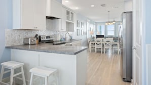 A modern kitchen with white cabinetry, a granite countertop, and a stainless steel refrigerator.
