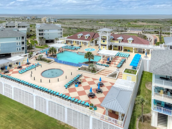 A resort with a large pool, sun loungers, and a view of the ocean.