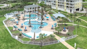 A resort with a large pool, multiple buildings, and a view of the ocean.