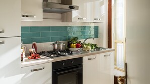 Une cuisine moderne avec des meubles blancs, une cuisinière à gaz, un évier et une fenêtre avec des rideaux.