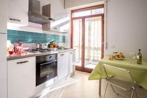 Una cocina moderna con estufa a gas, horno y comedor con mesa para dos.