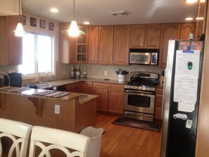 A modern kitchen with wooden cabinets, a stainless steel refrigerator, a microwave, an oven, and a sink. - SPECIAL DISCOUNT JUNE/SEPTEMBER/OCTOBER 4 days, pay for 3. Refund at booking. (Wildwood)
