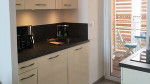 Eine kleine Küche mit weißen Schränken, einer schwarzen Arbeitsplatte und einer Kaffeemaschine.