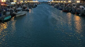 Ein schmaler Kanal, gesäumt von Booten und Gebäuden, mit spiegelnden Lichtern auf der Wasseroberfläche.