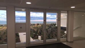 Ein modernes Hotelzimmer mit großen Schiebeglastüren, die auf einen Balkon mit Blick auf Strand und Meer führen.