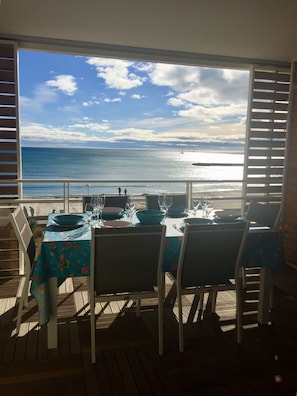 An outdoor dining area with a view of the ocean and a sailboat. - Sunny & spacious 2BR condo on beach 5min to shops (Palavas-les-Flots)