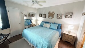 Une chambre à coucher comprenant un lit, des tables de chevet, un ventilateur de plafond et des éléments de décoration murale.