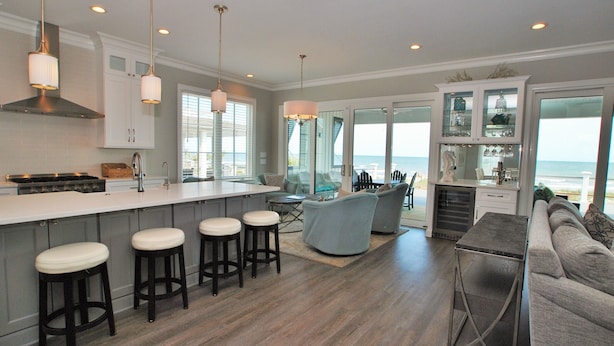 A modern kitchen with a large island, bar stools, and a view of the ocean. - OCEANFRONT / Sleeps 16 / BELLA VISTA / POOL / SPA / ELEVATOR / ELEGANT HOME (Isle of Palms)