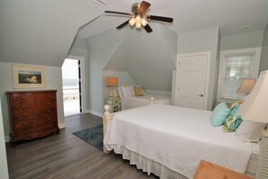 Un dormitorio con cama, cómoda, ventilador de techo y vistas al exterior.