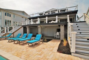 A modern house with a pool area featuring lounge chairs and a covered patio.