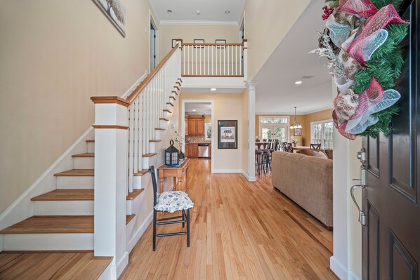 A spacious living area with a wooden staircase, a dining table with chairs, and a cozy seating area.