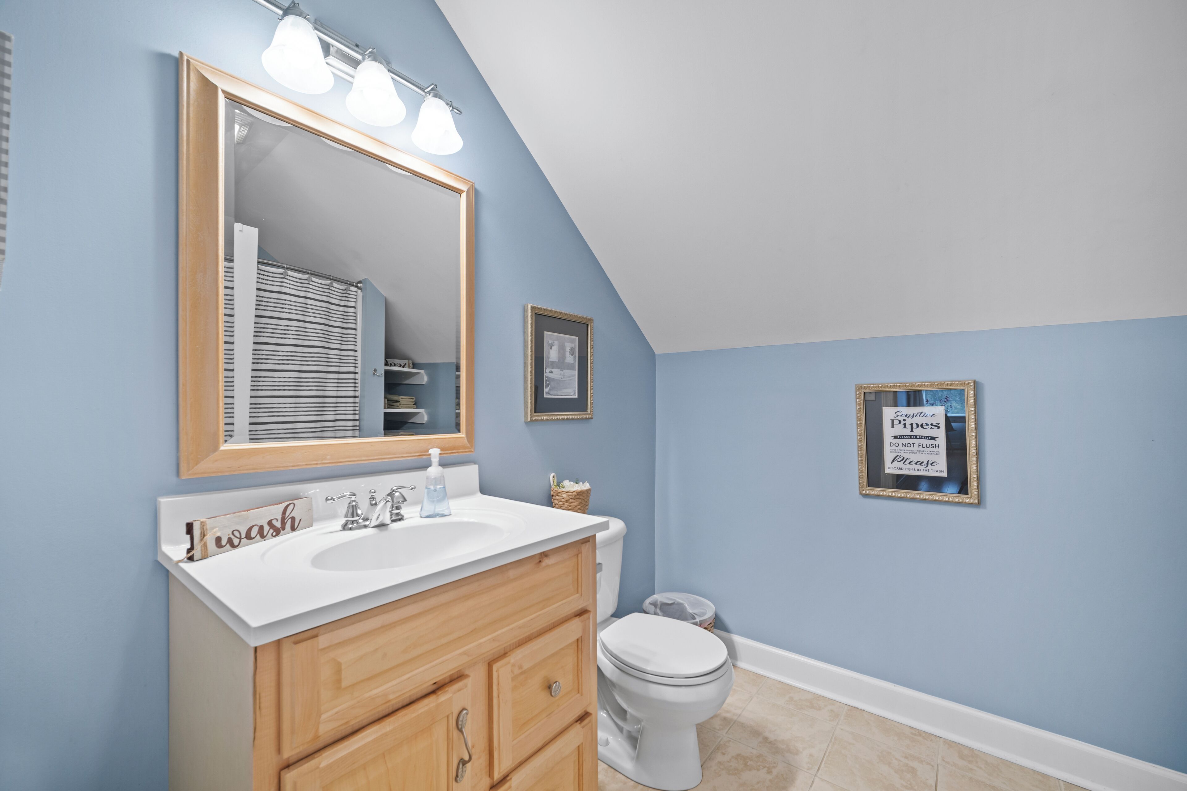 A bathroom with a white sink, wooden vanity, and a large mirror.