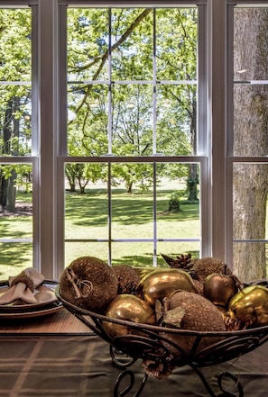 A window with a view of a green park and a tree trunk to the right.