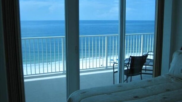 A bedroom with a large window overlooking a beach.