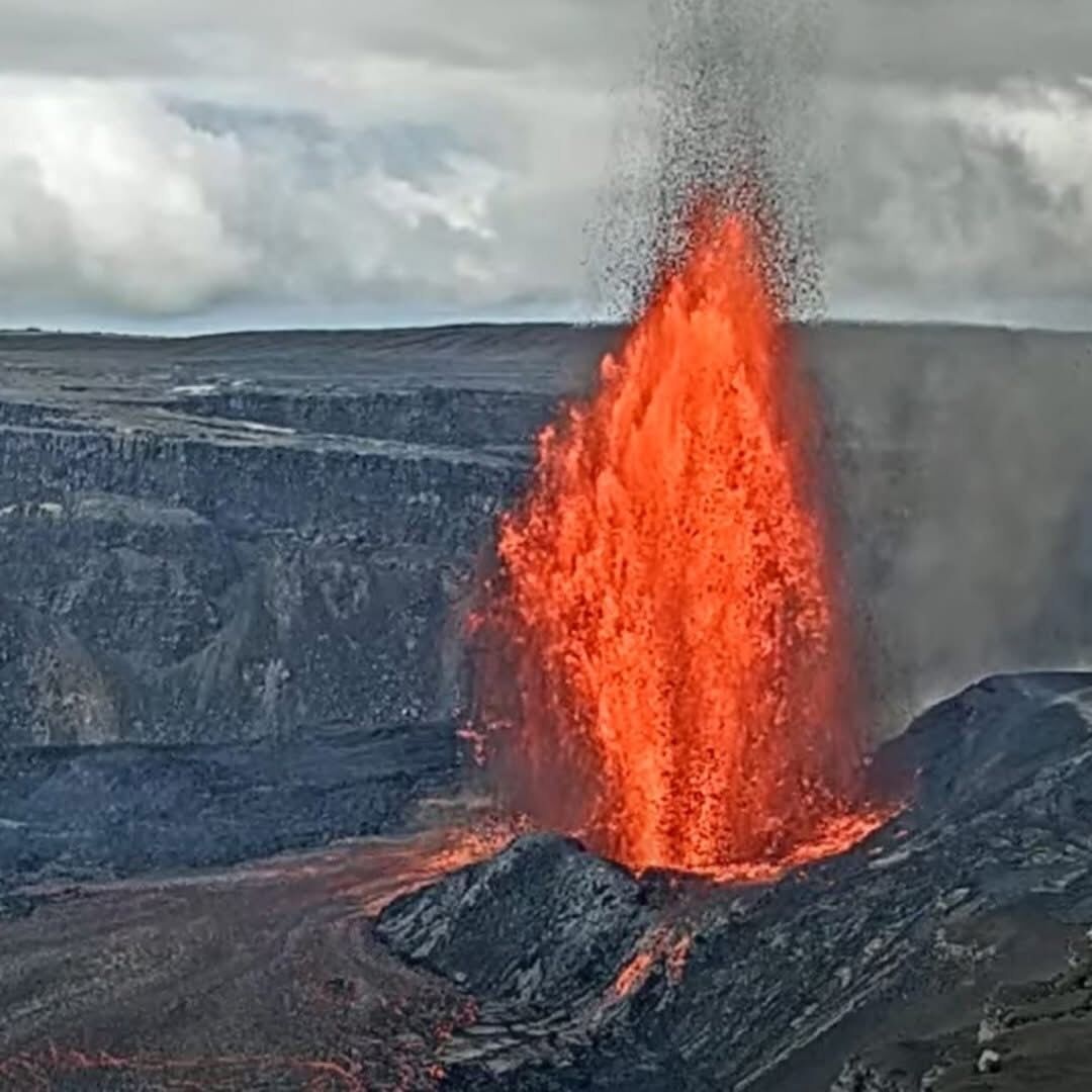 Una erupción volcánica con lava descendiendo por la ladera de un cráter.