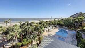 Um resort com área de piscina, palmeiras e vista para a praia.