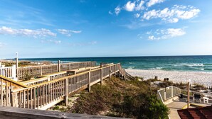 A wooden boardwalk leading to a beach with a clear view of the ocean. - Exclusive private home in gated community across the street from the beach. (PANAMA CITY BEACH)