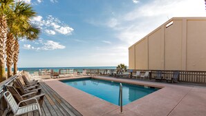 A pool area with lounge chairs, a wooden deck, and a view of the ocean. - Exclusive private home in gated community across the street from the beach. (PANAMA CITY BEACH)