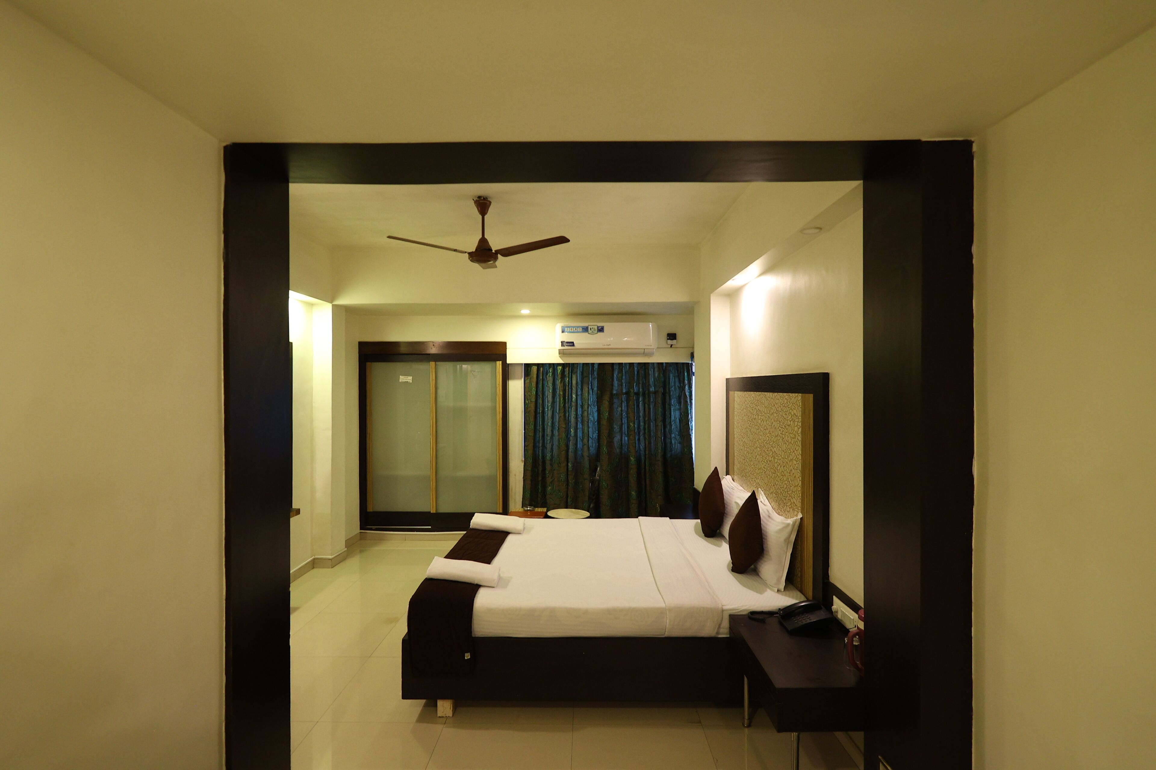 A bedroom with a bed, bedside table, and a ceiling fan.