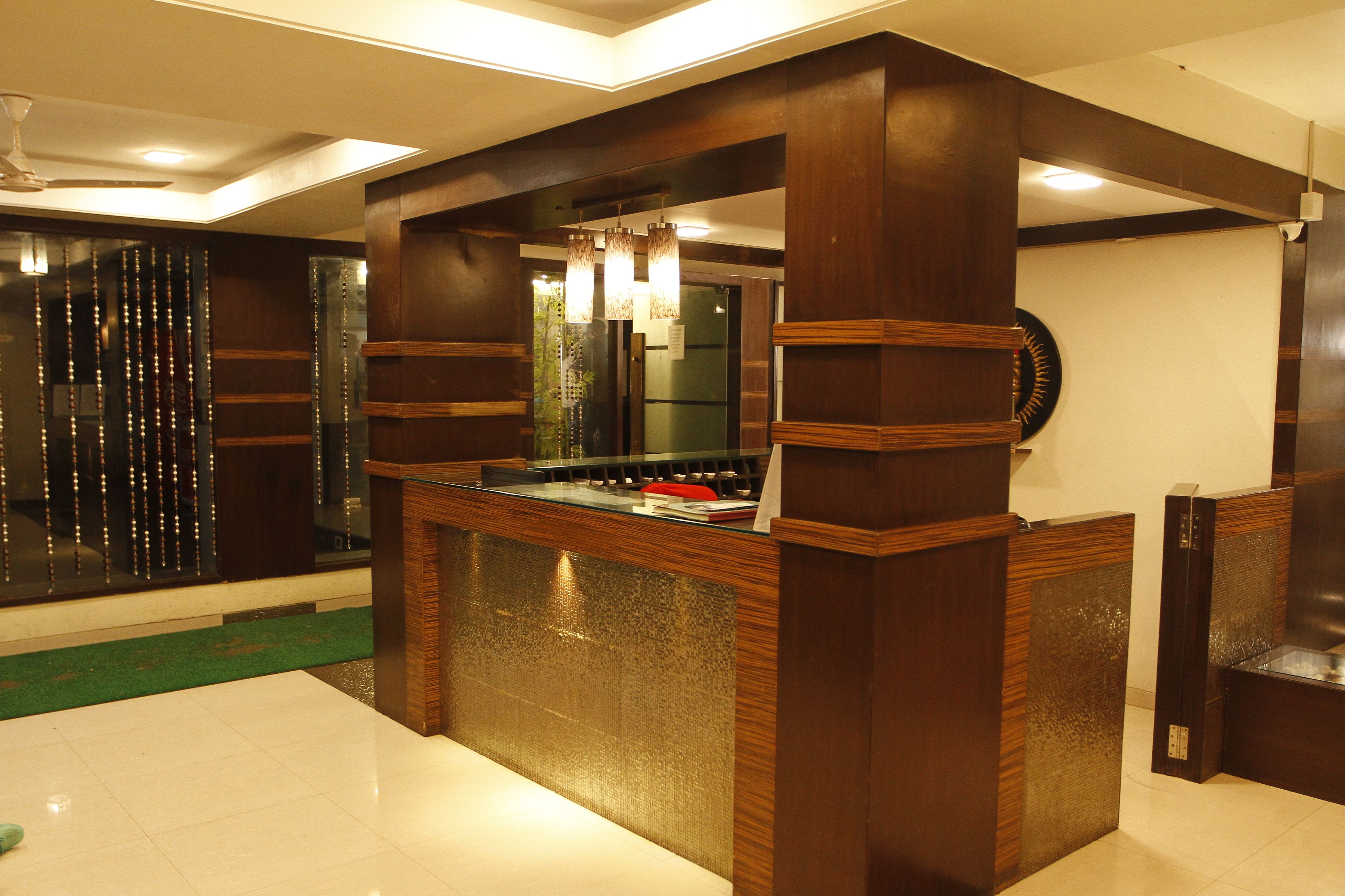 A reception desk with a glass top and wooden frame, a ceiling fan, and a green carpeted area.