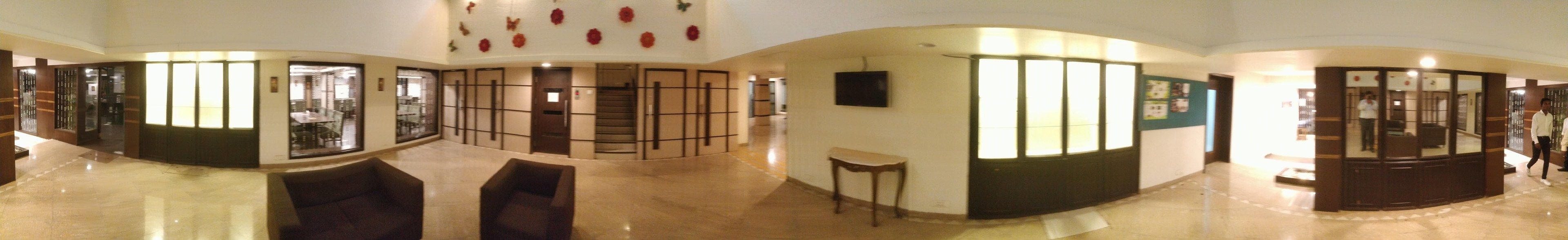 Un hall espacioso con distribución curva, una zona de estar y una escalera que lleva a un nivel superior.