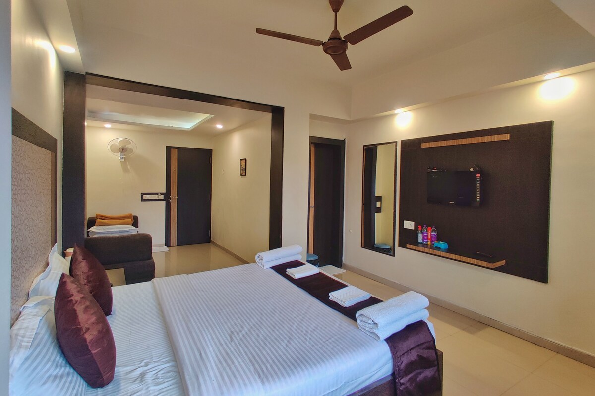 Une chambre d’hôtel avec un lit, un ventilateur de plafond, une télévision et un miroir.