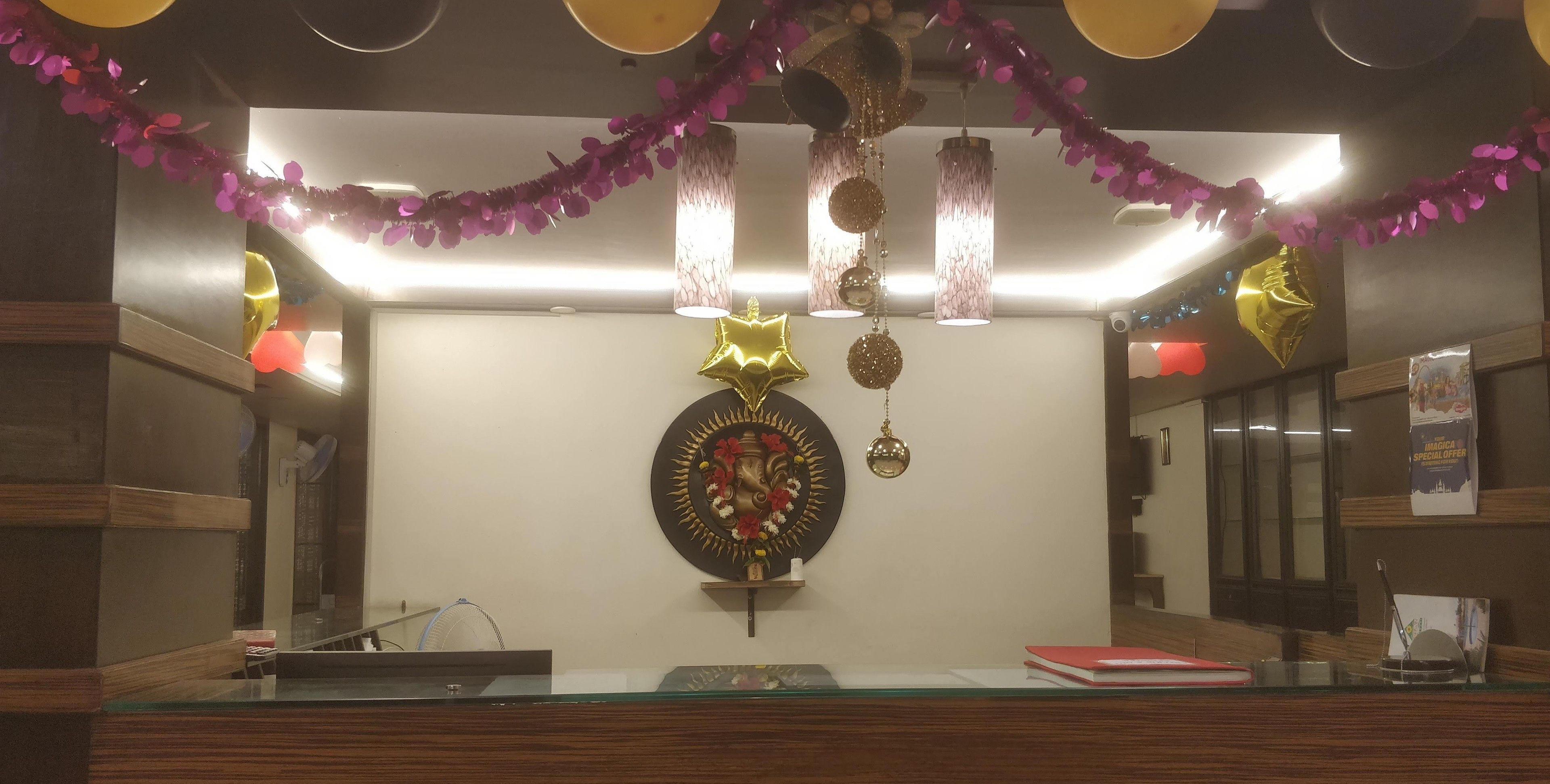 A reception area with a glass counter, a decorative wall hanging, and hanging ornaments.