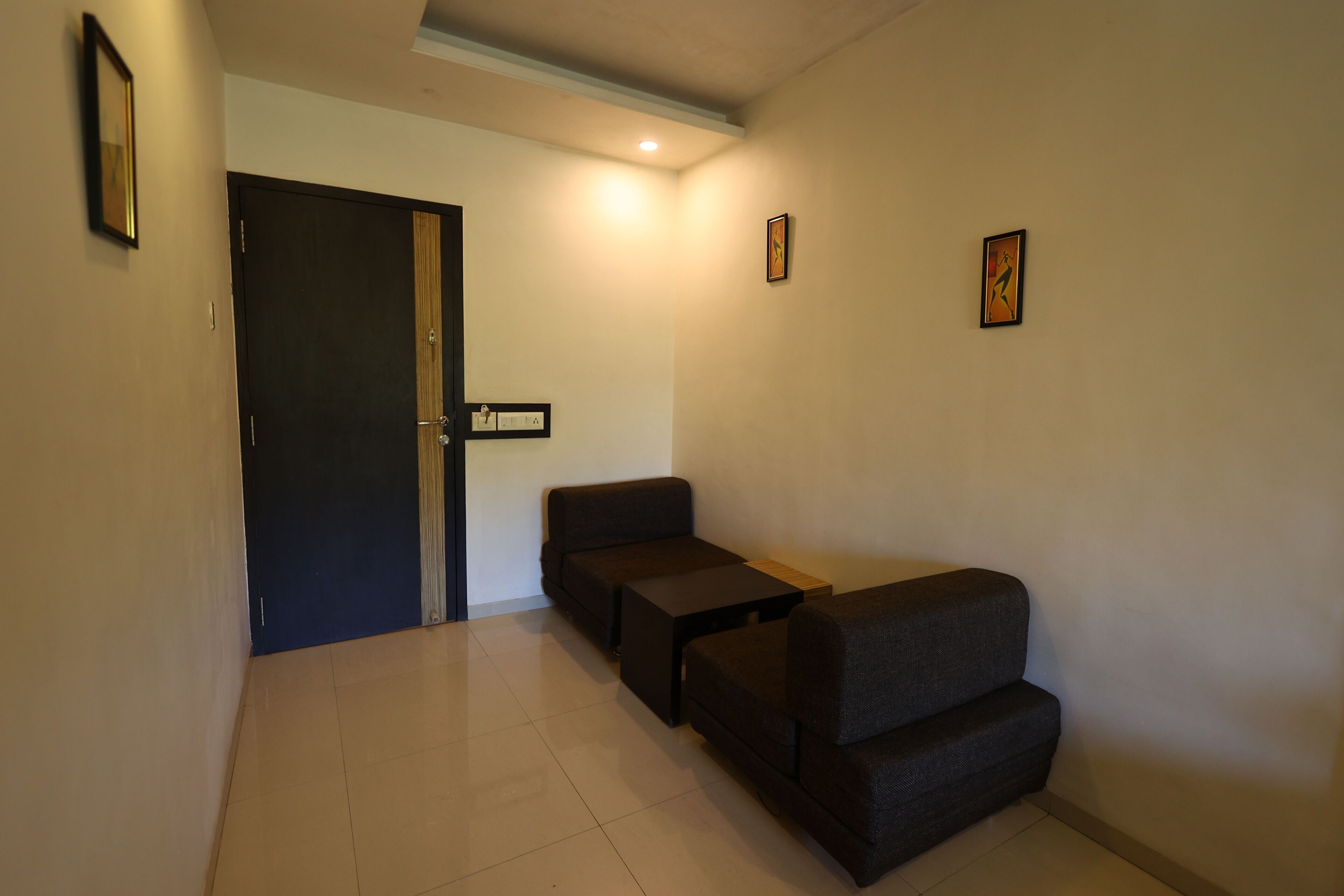 A hallway with a dark-colored door, a small table, and two dark-colored sofas.