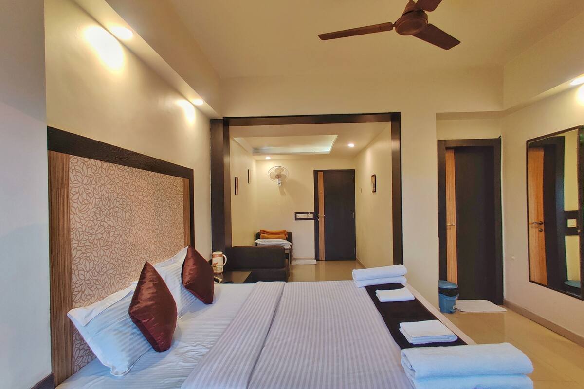 Habitación de hotel con una cama grande, ventilador de techo y vistas al pasillo.