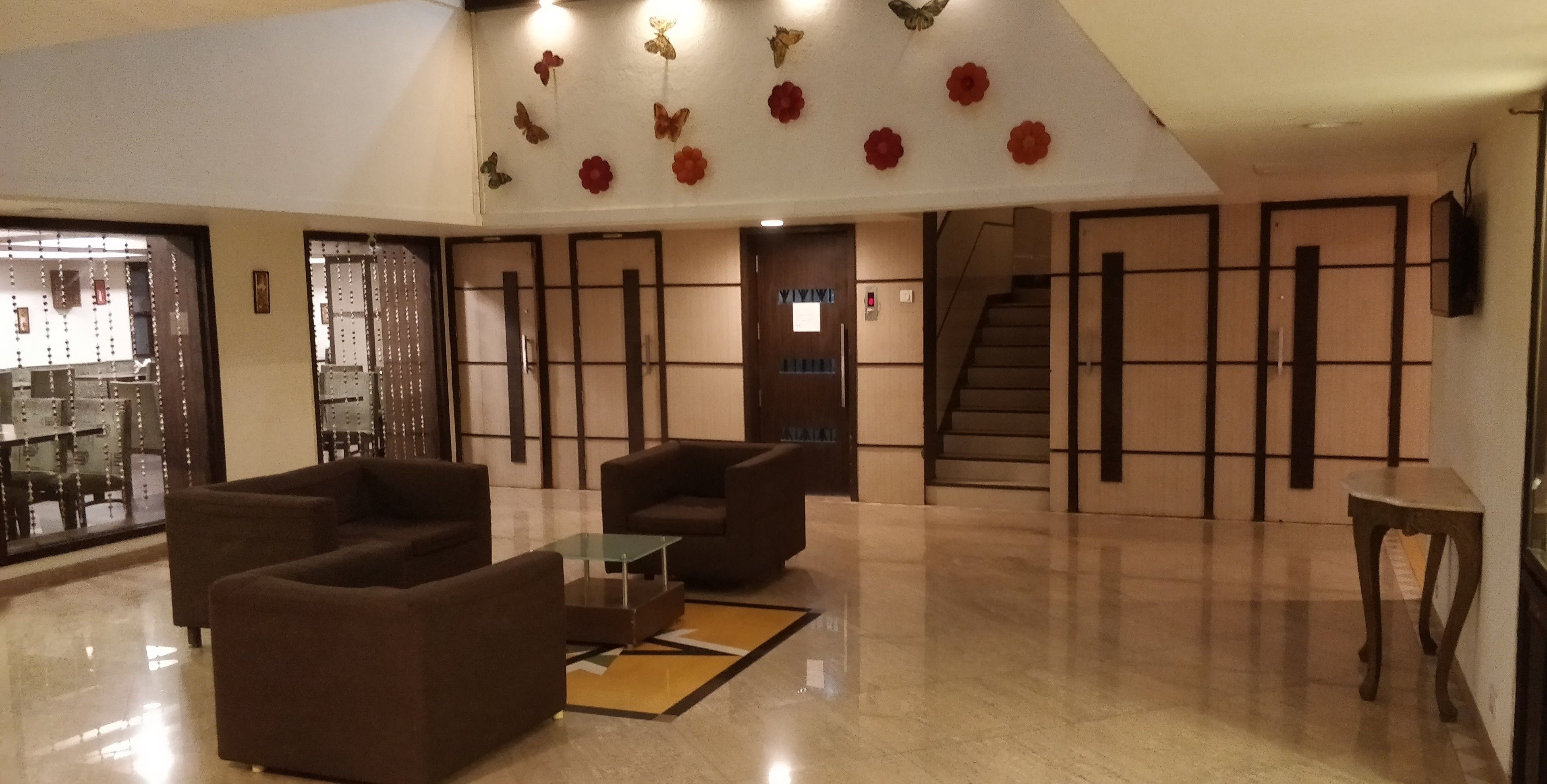A lobby with sofas, a coffee table, a staircase, and a wall with decorative elements.
