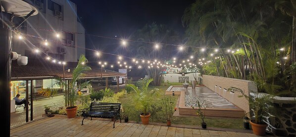 A courtyard with string lights, a water feature, and potted plants.