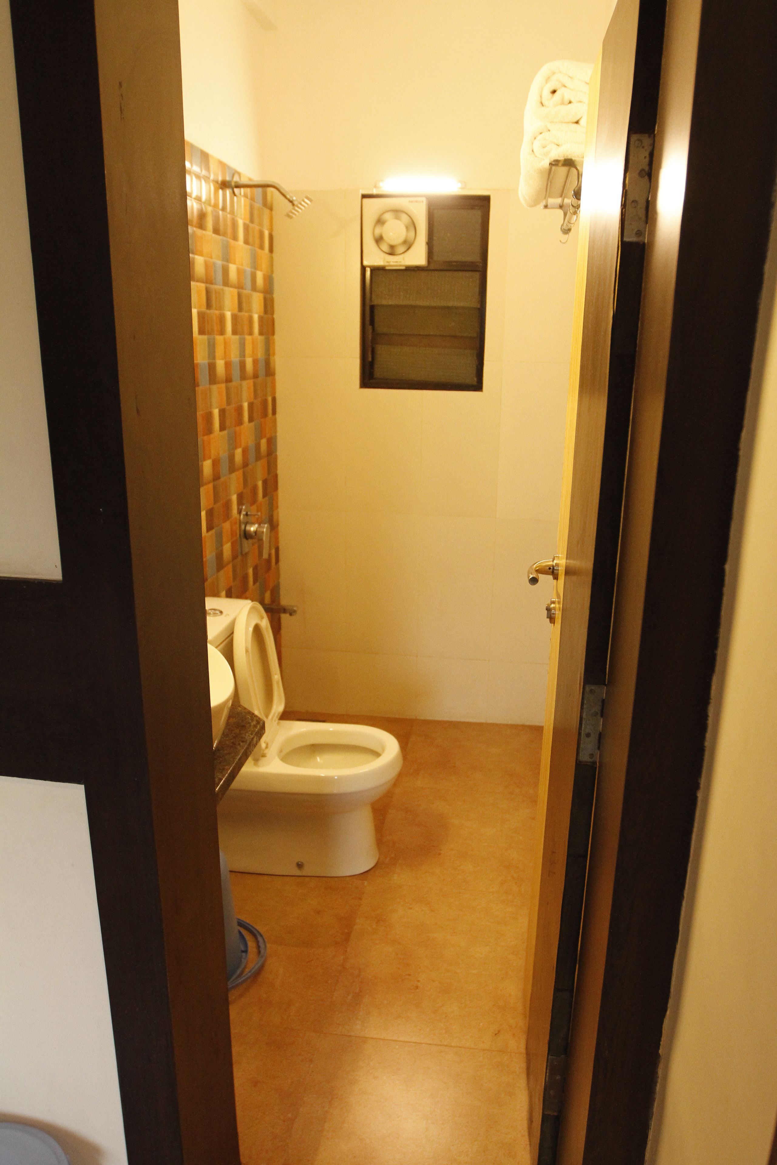 A small bathroom with a toilet, a shower area, and a towel rack.