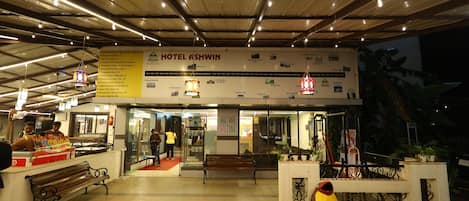 A hotel entrance with a sign reading "HOTEL GSHWIN," a bench, and a decorative planter with the text "USE ME."