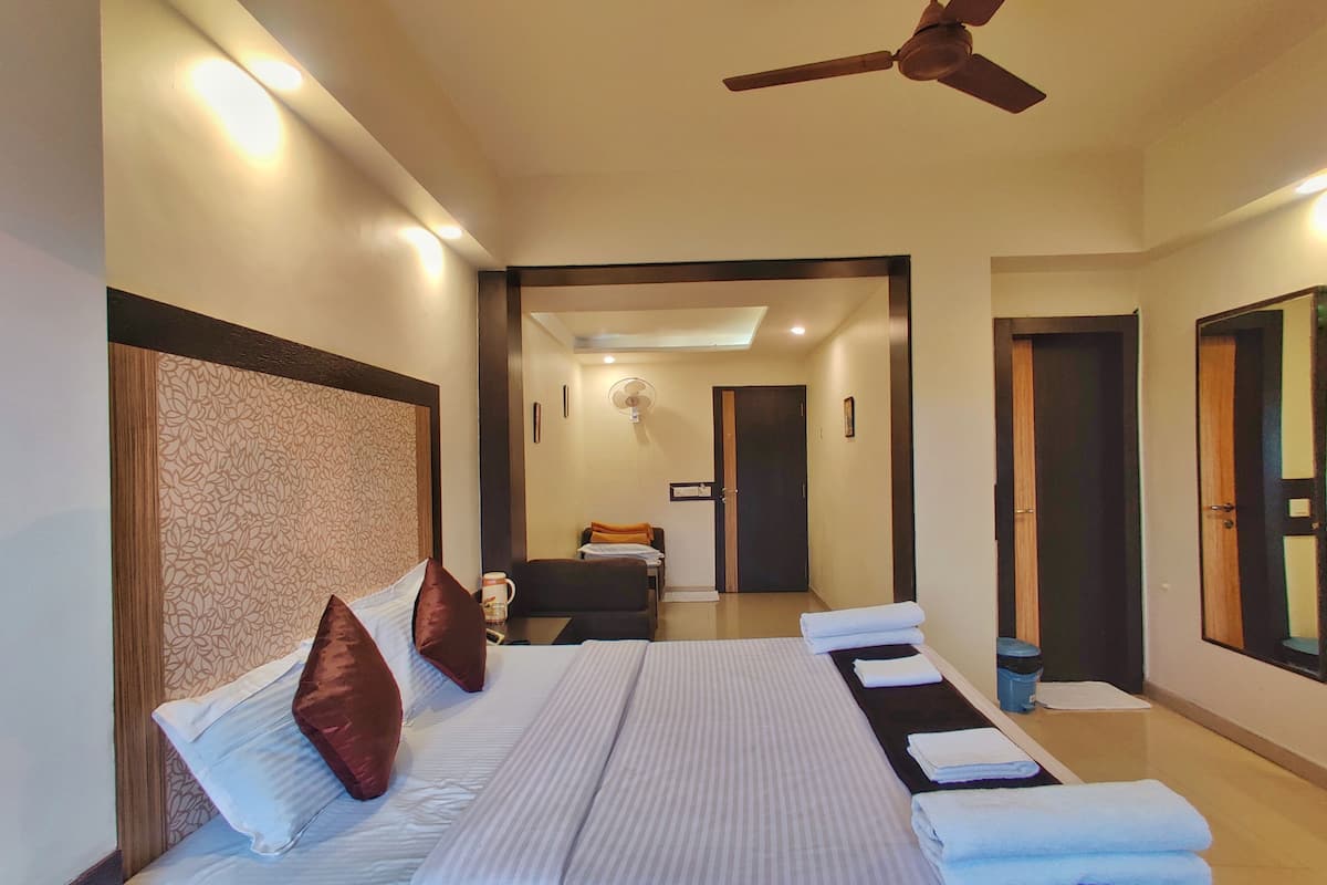 A hotel room with a large bed, a ceiling fan, and a view of the hallway.